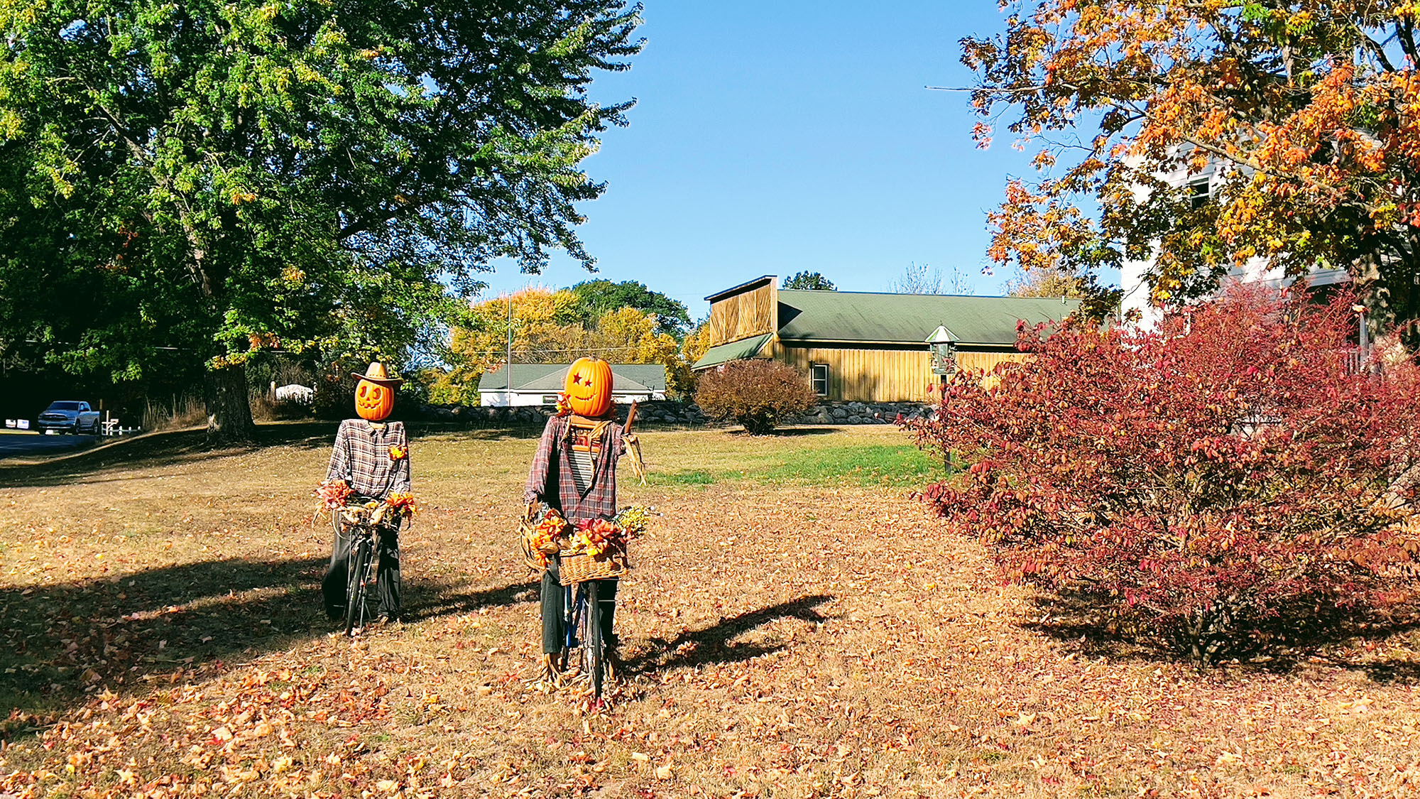 Pumpkin scarecrows on bikes with Almira Historical Society building in background